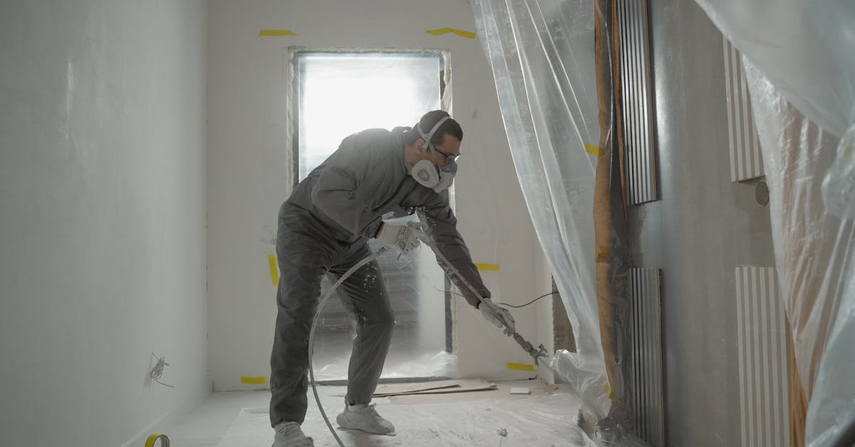 A worker in protective gear painting walls during an indoor renovation project.